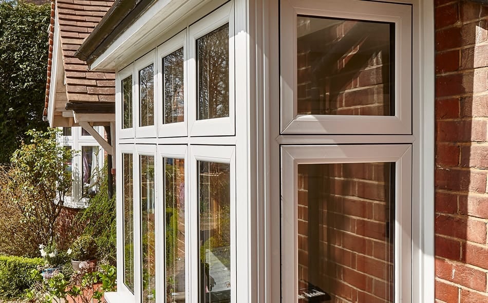 Modern grey aluminum patio doors with multiple glass panes on a brick house exterior, with climbing ivy visible on the left side.